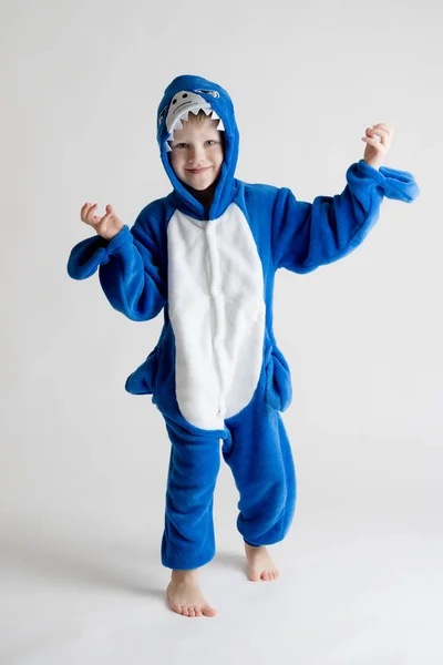 Veselý chlapeček pózuje na bílém pozadí v kigurumi pyžama, žralok modrý kostým — Stock fotografie