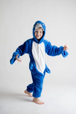neşeli küçük çocuk pijama, mavi köpekbalığı kostüm beyaz bir arka plan üzerinde poz