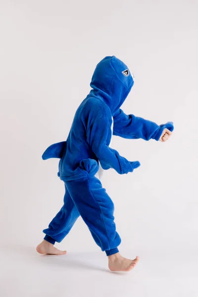 Glad liten pojke som poserar på en vit bakgrund i pyjamas, blue shark kostym — Stockfoto