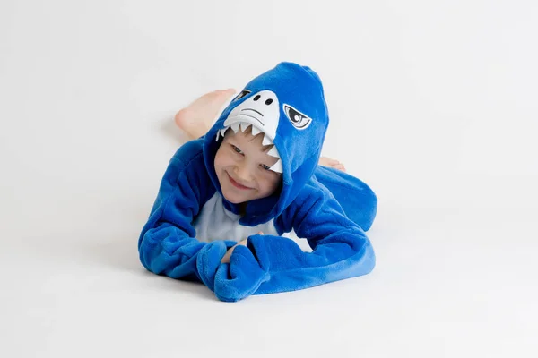 Fröhlicher kleiner Junge posiert auf weißem Hintergrund im Schlafanzug, blauem Hai-Kostüm — Stockfoto
