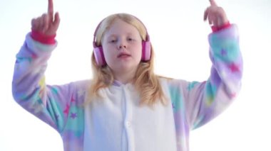 Modern moda - güzel sarışın kız beyaz bir arka plan üzerinde beyaz izole kigurumi pijama - dans ve kulaklık ile müzik dinler