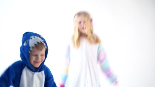 Kinderen dansen leuk op een witte achtergrond in pyjama's kigurumi — Stockvideo