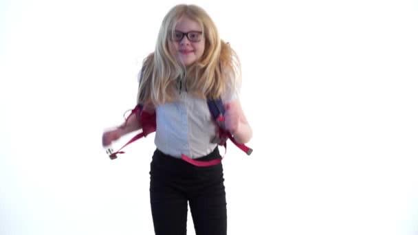 Beautiful schoolgirl with a school backpack and wearing glasses dancing in the studio on a white background — Stock Video