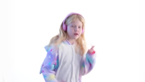 Mode moderne - belle fille blonde écoute de la musique avec écouteurs et danse sur un fond blanc en pyjama kigurumi - isolé sur blanc — Video