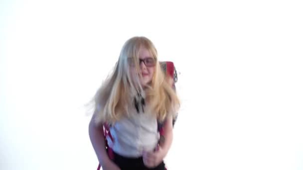 belle écolière avec un sac à dos scolaire et portant des lunettes dansant en studio sur fond blanc .