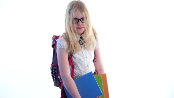 Belle écolière avec un sac à dos scolaire et portant des lunettes posant en studio sur fond blanc — Video