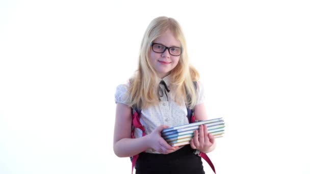 Красивая школьница со школьным рюкзаком и в очках позирует в студии на белом фоне — стоковое видео