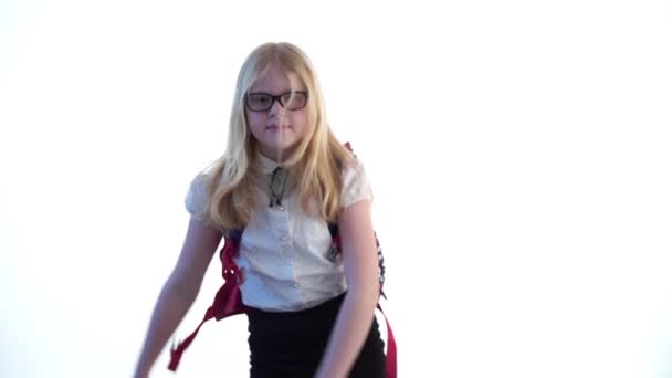 Красивая школьница со школьным рюкзаком и в очках танцует в студии на белом фоне — стоковое видео