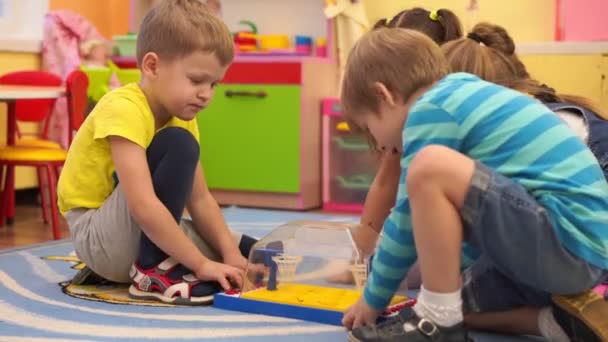Educación preescolar - niños felices en el jardín de infantes se divierten jugando juntos — Vídeo de stock