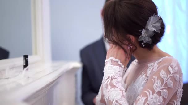Невеста корректирует макияж у зеркала в шикарной комнате — стоковое видео