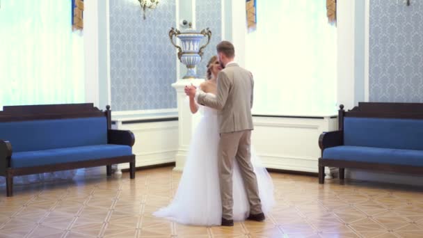 Schöne blonde Braut dreht sich in einem Hochzeitskleid in einem schicken Zimmer — Stockvideo