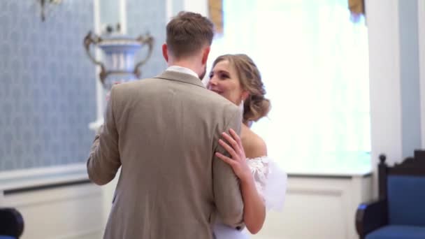 ウェディング ドレスで美しい金髪の花嫁がシックな部屋で彼女の婚約者と一緒に踊っています。 — ストック動画