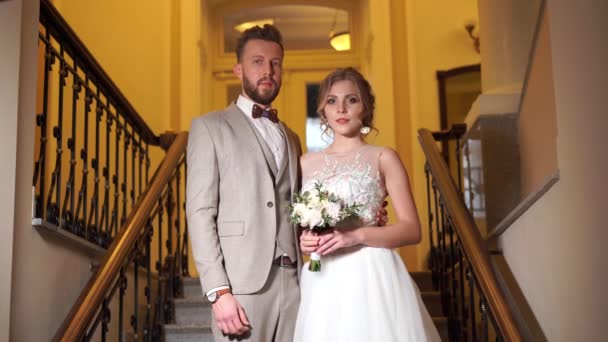 Krásný novomanželský pár pózuje v drahé elegance krytý na schodech — Stock video