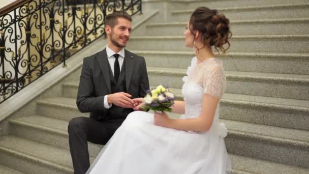 Hermosa pareja recién casada posando en el elegante interior caro en los escalones — Vídeo de stock