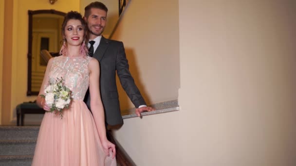 Hermosa pareja recién casada posando en el elegante interior caro en los escalones — Vídeos de Stock