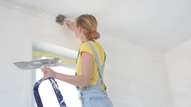Reparation i lägenheten-en ung kvinna av europeiskt utseende gör reparationer hemma — Stockvideo