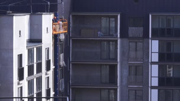 Покраска высотных зданий - рабочие в строительной колыбели — стоковое видео
