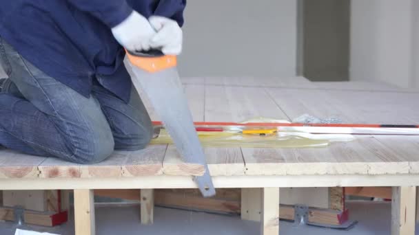 Trabalhos de construção - um homem serrar tábuas de madeira serrada piso — Vídeo de Stock