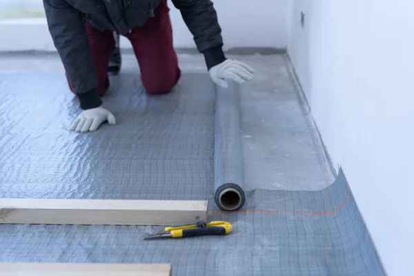 Mistrz stolarz montuje podłogę z drewna sosnowego-ekologiczne podłogi. klejenie warstwy izolacji pod opóźnieniem na betonie. — Zdjęcie stockowe