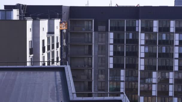 Pintura edifícios de arranha-céus - trabalhadores no berço da construção — Vídeo de Stock