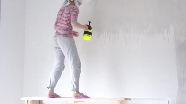 Reparation i lejligheden en ung kvinde af europæisk udseende gør reparationer derhjemme væg priming – Stock-video