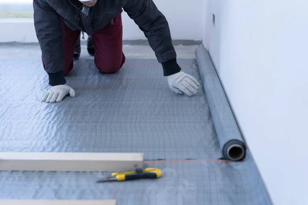 Master Carpenter mounts grenen houten vloer-eco-vriendelijke vloeren. het lijmen van de isolatie laag onder de lag op het beton. — Stockfoto