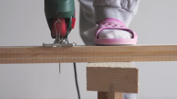 Beauty of slow motion in construction and repair - man sawing a wooden board with an electric jigsaw closeup — Stock Video