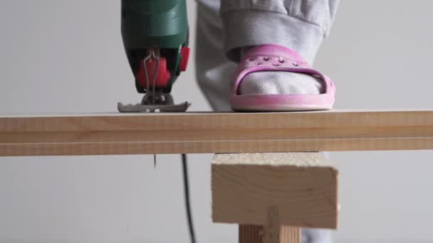 Beauty of slow motion in construction and repair - man sawing a wooden board with an electric jigsaw closeup — Stock Video