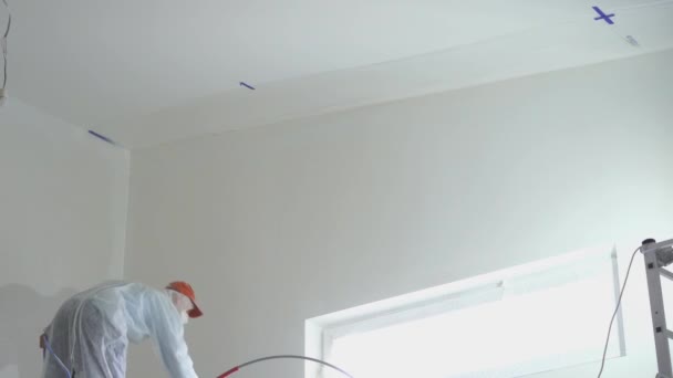 Reparación del apartamento - pintor profesional pinta las paredes con pistola de pintura blanca — Vídeo de stock