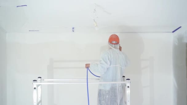 Schönheit in Zeitlupe. Reparatur der Wohnung - professioneller Maler streicht die Wände mit weißer Farbspritzpistole — Stockvideo