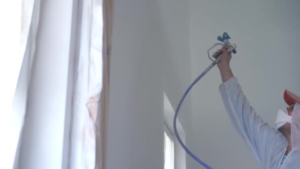 美しさスローモーション。アパートの修理 - プロの画家は白い塗料スプレー銃で壁をペイント — ストック動画