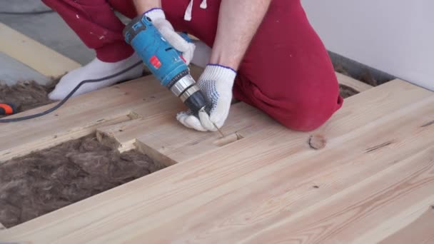 Houtbewerking in het huis-een jonge professionele man mounts een grenen houten vloer — Stockvideo