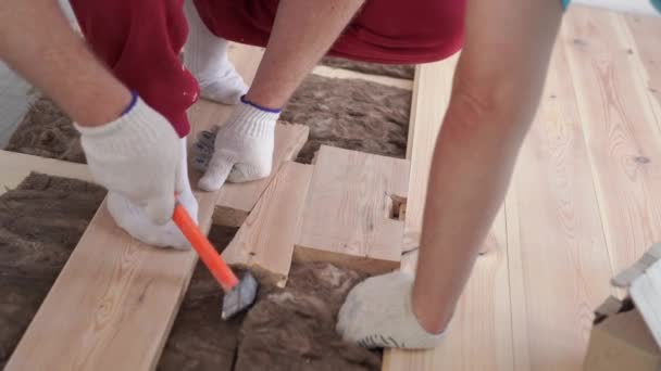 Houtbewerking in het huis-een jonge professionele man mounts een grenen houten vloer — Stockvideo