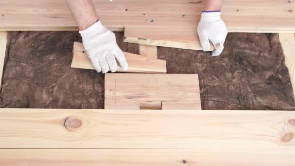 Lavorazione del legno in casa - un giovane professionista monta un pavimento in legno di pino — Video Stock