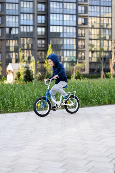 Seguridad en una ciudad europea moderna. Un niño feliz monta una bicicleta a través de un patio cerrado en un edificio urbano de varios pisos . — Foto de Stock