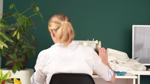 Lavorare a casa. giovane donna bionda cuce su una macchina da scrivere in una stanza luminosa — Video Stock