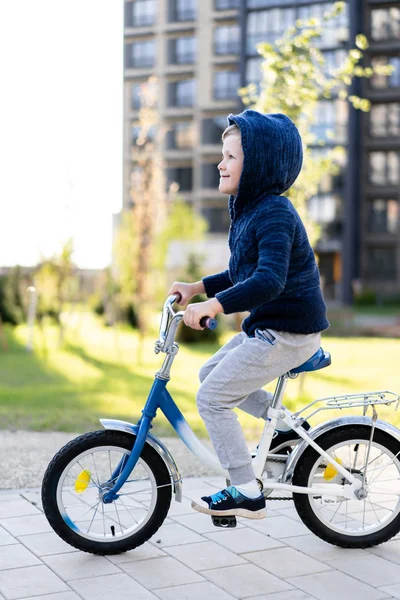Безопасность в современном европейском городе. Маленький счастливый мальчик едет на велосипеде через закрытый двор в многоэтажном городском здании . — стоковое фото