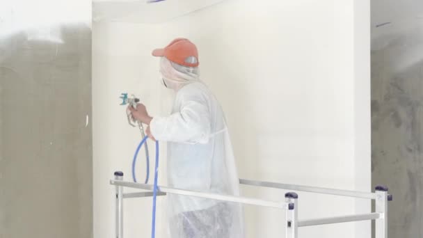 Réparation de l'appartement - peintre professionnel peint les murs avec pistolet à peinture blanche — Video