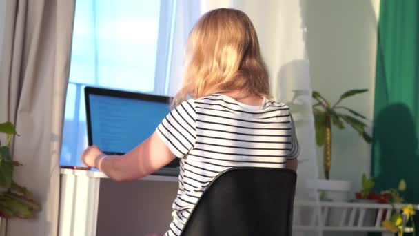 Télétravail à la maison. la femme dans la chambre est assise à un ordinateur portable et fait une commande en ligne. Intérieur scandinave moderne et lumineux avec plantes vivantes . — Video