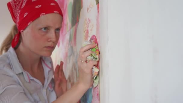 Réparation et décoration appartement. femme colle photo papier peint sur le mur . — Video