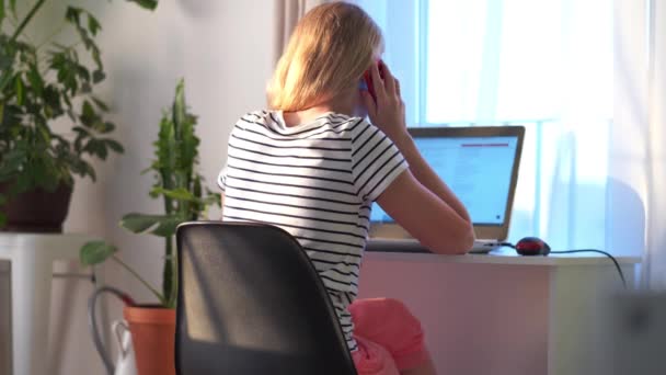 Thuis op afstand werken. de vrouw in de kamer zit op een laptop en maakt een bestelling online. Modern helder Scandinavisch interieur met levende planten. — Stockvideo