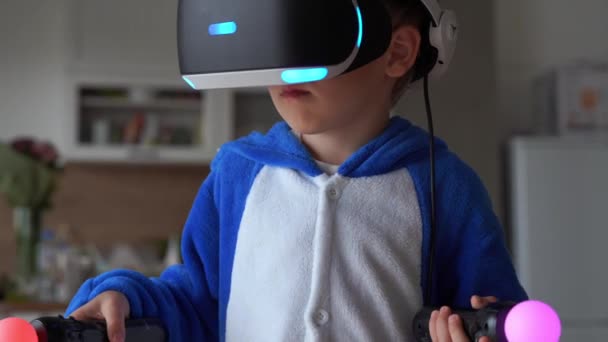 La vida moderna de la juventud. La última tecnología electrónica en la vida cotidiana. niño pequeño juega en casa en un casco de realidad virtual — Vídeo de stock