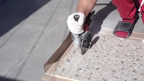 Reparação e decoração de apartamentos e casas. homem corta moedor de telha de porcelana no terraço — Vídeo de Stock