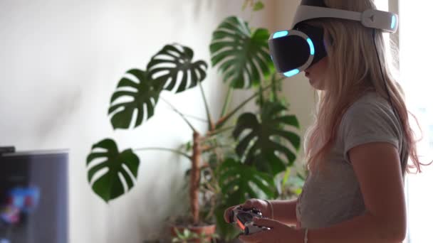 Сучасне життя молоді. Останні електронні технології в повсякденному житті. дівчина-підліток грає вдома у шоломі віртуальної реальності — стокове відео