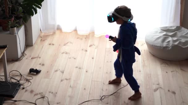 La vida moderna de la juventud. La última tecnología electrónica en la vida cotidiana. niño pequeño juega en casa en un casco de realidad virtual — Vídeos de Stock