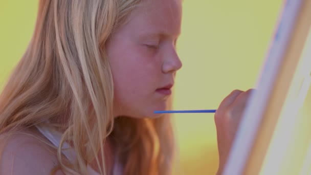 Mooi blond tiener meisje schildert een beeld op het terras — Stockvideo