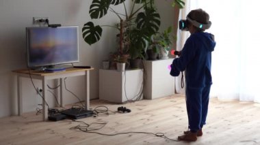 modern gençlik hayatı. Günlük hayattaki en son elektronik teknoloji. Küçük çocuk evde sanal gerçeklik kaskıyla oynuyor.