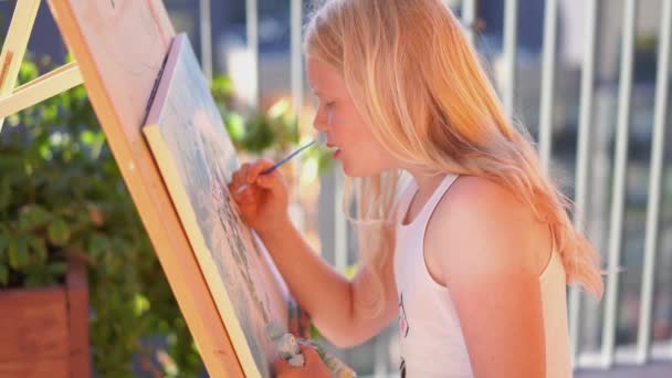 Güzel sarışın genç kız terasa bir resim çiziyor. — Stok video