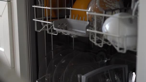 A woman opens a dishwasher and puts a dirty plate in it — Stock Video