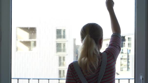 Молодая женщина чистит окно — стоковое видео